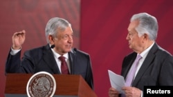 Mexico's President Andres Manuel Lopez Obrador chat with Manuel Bartlett (CFE) during an event where the government reached a deal with companies to renegotiate terms of natural gas pipeline contracts, Aug. 27, 2019.