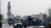 FILE - A military convoy travels along the main road of Kandahar as seen from the glass window of a U.S. military armored vehicle, in Afghanistan, Oct. 5, 2010. 