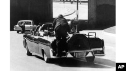 ARCHIVO - El agente de servicio secreto Clint Hill empuja a la primera dama Jacqueline Kennedy hacia de vuelta a su asiento luego que el presidente John F. Kennedy recibe un disparo en la limusina presidencial en Dallas, Texas, el 22 de noviembre de 1963.