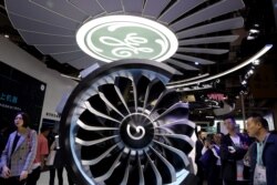 Visitors look at a turbine engine displayed at the General Electric booth during China International Import Expo in Shanghai, Nov. 6, 2019.