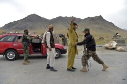 Afghan National Army soldiers search men at a road checkpoint on the outskirts of Kabul on April 29, 2021.