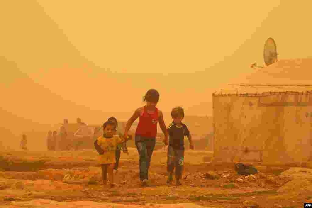 Syrian children walk amid the dust during a sandstorm at a refugee camp on the outskirts of the eastern Lebanese city of Baalbek.