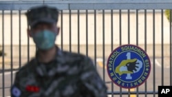 In this Feb. 21, 2020, photo, a South Korean marine wearing a mask stands in front of the Navy Base after a soldier of the unit was confirmed to have been infected with the coronavirus on Jeju Island, South Korea.