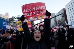 Para peserta merayakan setelah mendengar berita bahwa parlemen Korea Selatan telah memberikan suara untuk memakzulkan Presiden Yoon Suk Yeol di luar Majelis Nasional di Seoul, Korea Selatan, Sabtu, 14 Desember 2024. (Foto: AP)