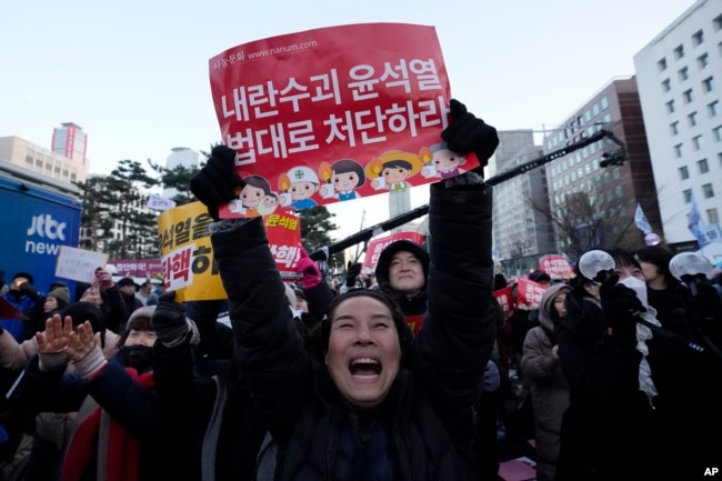 Para peserta merayakan setelah mendengar berita bahwa parlemen Korea Selatan telah memberikan suara untuk memakzulkan Presiden Yoon Suk Yeol di luar Majelis Nasional di Seoul, Korea Selatan, Sabtu, 14 Desember 2024. (Foto: AP)