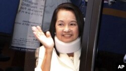 Former President Gloria Macapagal Arroyo waves to the crowd as she comes to a court arraignment at the Regional Trial Court in suburban Pasay City south of Manila.