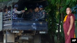 A Buddhist monk stands next a truck full of police officers during a gathering at a courthouse in support of five Buddhist monks who were forced to give up their robes in Yangon, Myanmar, also known as Burma, June 20, 2014.