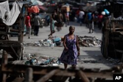 FILE - People walk through a market street, where wooden stands were used by protesters to barricade the road, in central Port-au-Prince, Haiti, Oct. 2, 2019.