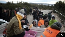 Migrants queue to get free food as they wait to travel to Greek islands by dinghies, near Cesme, Izmir, Turkey, late Thursday Dec. 31, 2015.