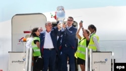 L’entraîneur du Portugal Fernando Santos, à gauche, et le capitaine Cristiano Ronaldo, à droite, sortent de l’avion brandissant le trophée de l’Euro 2016, à l'aéroport Humberto Delgado à Lisbonne, Portugal, 11 juillet 2016. epa / MARIO CRUZ