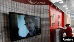 Sebuah layar televisi menyiarkan gambar mantan kontraktor badan intelijen AS Edward Snowden di sebuah kafe di bandar udara Moskow (26/6).