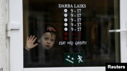 FILE - A boy looks through a shop window in Valka, Latvia, Oct. 25, 2013.