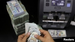 FILE: A money exchange vendor counts U.S. dollar banknotes , May 24, 2022