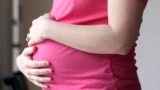 FILE - A pregnant woman stands for a portrait in Dallas, May 18, 2023. (AP Photo/LM Otero, File)