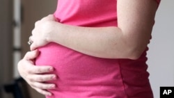 FILE - A pregnant woman stands for a portrait in Dallas, May 18, 2023. (AP Photo/LM Otero, File)