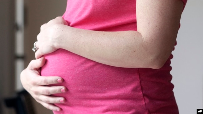 FILE - A pregnant woman stands for a portrait in Dallas, May 18, 2023. (AP Photo/LM Otero, File)