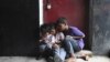 Children play on a cell phone at a market in New Delhi, India.