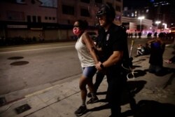 A police officer arrests a woman as protests over the death of George Floyd continued May 31, 2020, in Los Angeles.