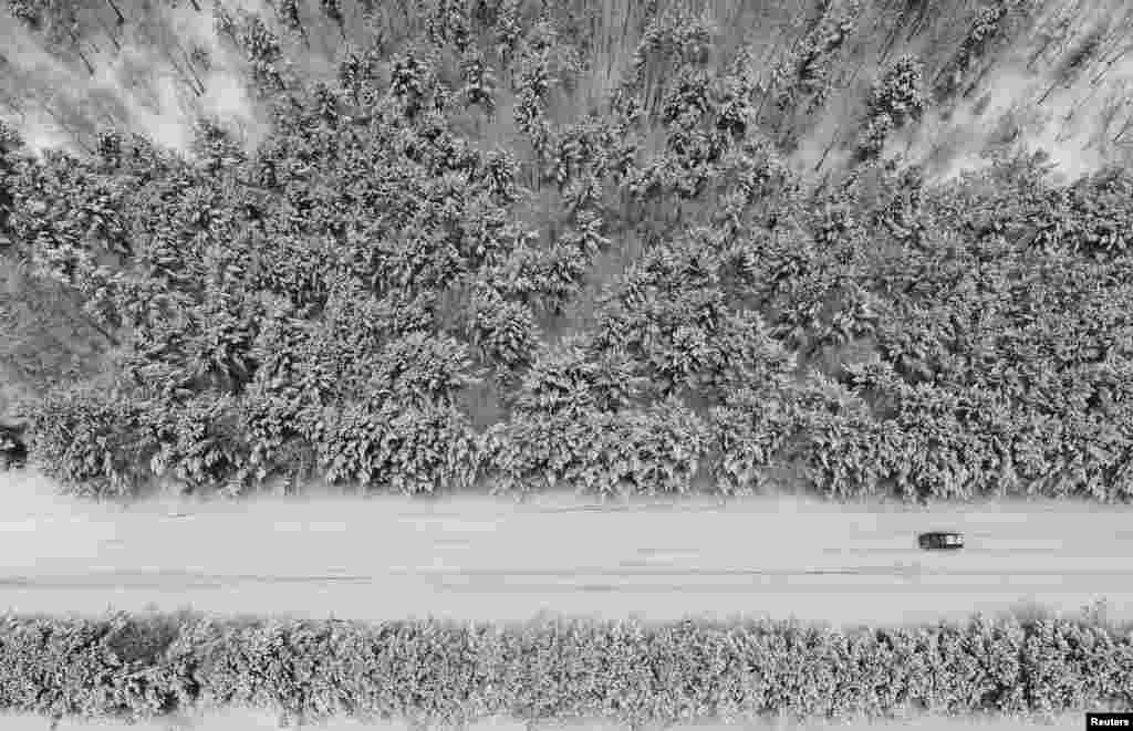 A car drives along a forest road after snowfall outside Krasnoyarsk, Russia.