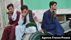 Afghan men sit in a courtyard inside a Shiite mosque in Kandahar on Oct. 15, 2021, after a suicide bomb attack during Friday prayers that killed more than 30 people. 