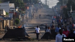 Residents walk past barricades that were used by protesters after the ruling Frelimo party was declared the winner of this month's disputed presidential election, in Maputo, Mozambique, Oct. 25, 2024.