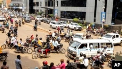 Drivers of motorcycle taxis, known locally as boda-bodas, ride with passengers on a street of Kampala, Uganda, on July 18, 2024. 