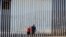 Two people walk towards metal bars marking the United States border where it meets the Pacific Ocean, March 2, 2016, in Tijuana, Mexico. 