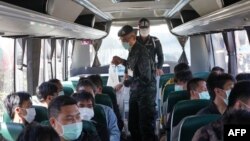 This handout photo taken and released on Nov. 18, 2023 by the Royal Thai Army shows Thai military personnel with some of the 41 Thai nationals on a bus to Mae Sai after they returned to Thailand after being trapped in Myanmar.
