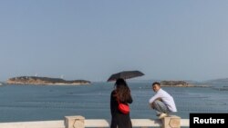 FILE - People stand on a viewing platform overlooking the Taiwan strait on Pingtan Island, Fujian province, China, April 10, 2023. 