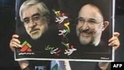 Участница протестов держит плакат с изображением лидеров иранской оппозиции