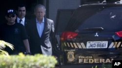 Jose Dirceu, former presidential chief of staff, center, is accompanied by federal police agents to a car at a police station in Brasilia, Aug. 4, 2015.