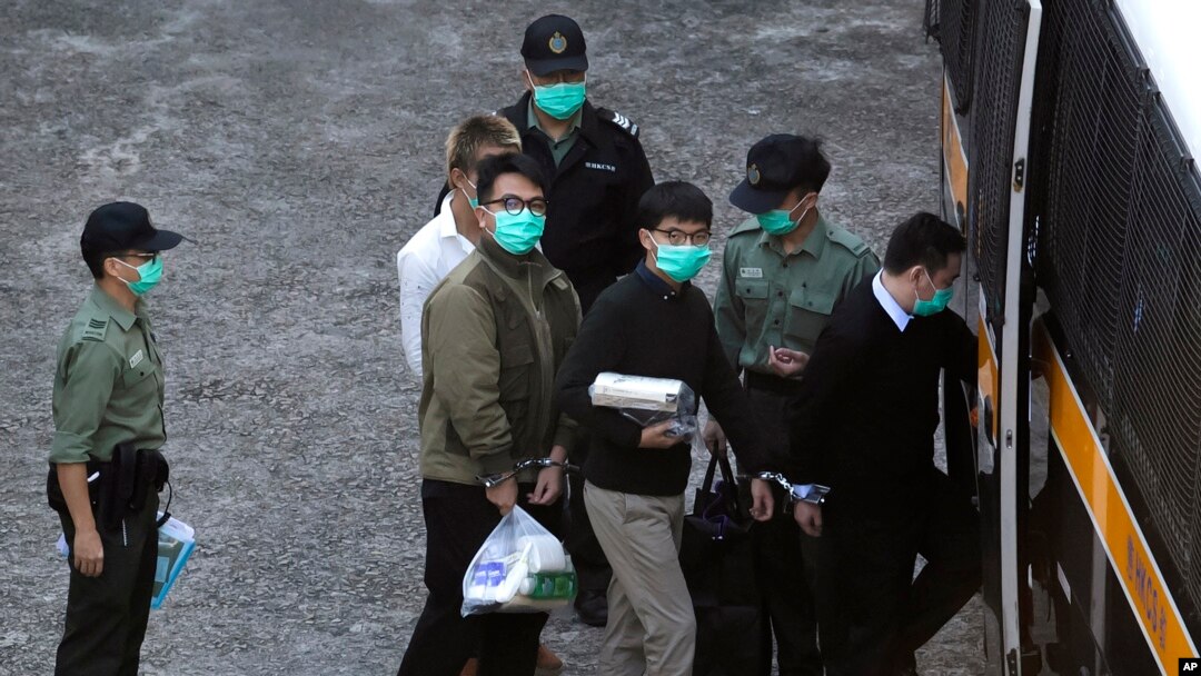 Aktivis Hong Kong Joshua Wong (kanan) dan Ivan Lam (kiri) dikawal oleh petugas Layanan Pemasyarakatan menuju van penjara sebelum disidang di pengadilan Hong Kong, Rabu, 2 Desember 2020. (Foto: dok).
