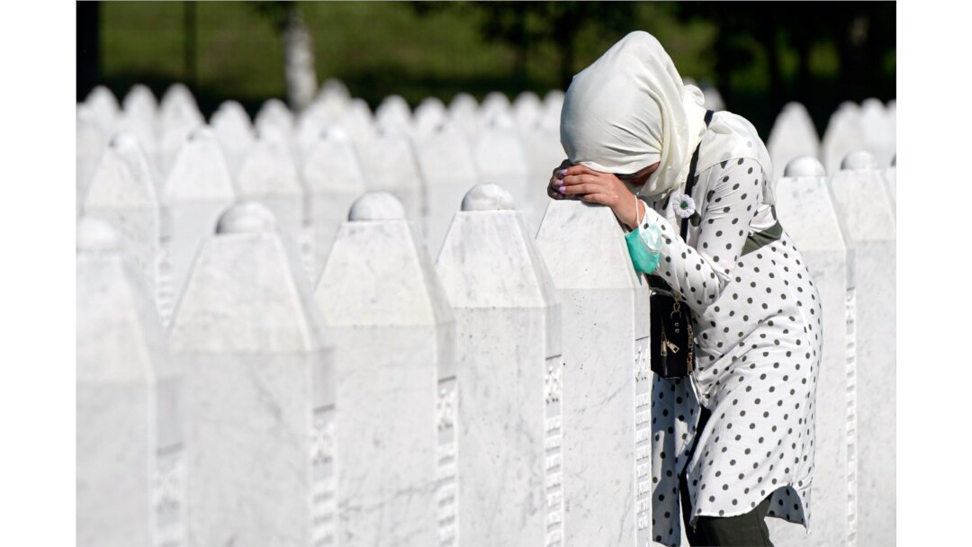 A woman leans on a grave stone in Potocari, near Srebrenica, Bosnia, July 11, 2020.
