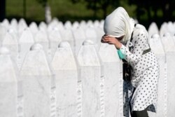 A woman leans on a grave stone in Potocari, near Srebrenica, Bosnia, July 11, 2020.