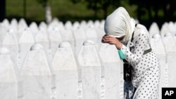 A woman leans on a grave stone in Potocari, near Srebrenica, Bosnia, July 11, 2020. Nine newly found and identified men and boys were laid to rest as Bosnians commemorate 25 years since more than 8,000 Bosnian Muslims perished in 10 days of slaughter.