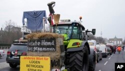 FILE— Farmers block a street with their tractors at the Brandenburg Gate during a Farmer's protest in Berlin, Germany, March 22, 2024. Signs reading "Lying, Cheating, Stealing, Failing, Government" and "Traffic-Light Government must go."