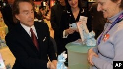 Ty Warner, left, Beanie Baby creator and chief executive of Ty Inc., gives "Decade," the 10th anniversary baby bear, to Debbie, far right, of Bel Air, Maryland, after signing his name to the attached tag in New York. (2003 file photo) 