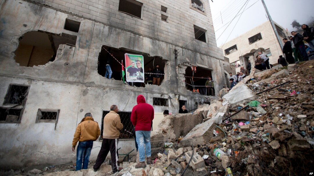 Palestinians gather by a destroyed house of Raeb Ahmed Muhammad Alivi that was demolished by the Israeli army in the West Bank city of Nablus, Thursday, Dec. 3, 2015.