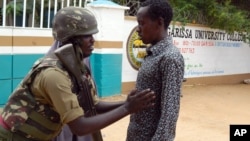 An armed security officer checks a student entering the Garissa university college, in Garissa, Kenya, on Jan. 4, 2016. 