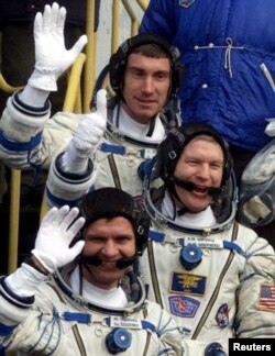 FILE - Russian cosmonauts Sergei Krikalyov (Top), Yuri Gidzenko and U.S. astronaut Bill Shepherd (C) wave hands before the launch at Baikonur.
