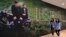 In this March 15, 2018, photo, two women walk past a mural of a Paul Fusco photograph that is part of the exhibit, "The Train: RFK's Last Journey," at the San Francisco Museum of Modern Art in San Francisco.
