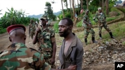 FILE— In this file photo taken November 27, 2012, Congolese M23 rebel fighters detain a man they suspect to be an FDLR (Force Democratique de Liberation du Rwanda) rebel returning from an incursion into Rwanda Near Kibumba, north of Goma.