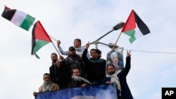 Protestors wave Palestinian flags during a rally supporting Palestinian President Mahmoud Abbas, shown in banner, and against the Mideast plan announced by U.S. President Donald Trump, at the Unknown Soldier Square in Gaza City, Feb. 11, 2020.