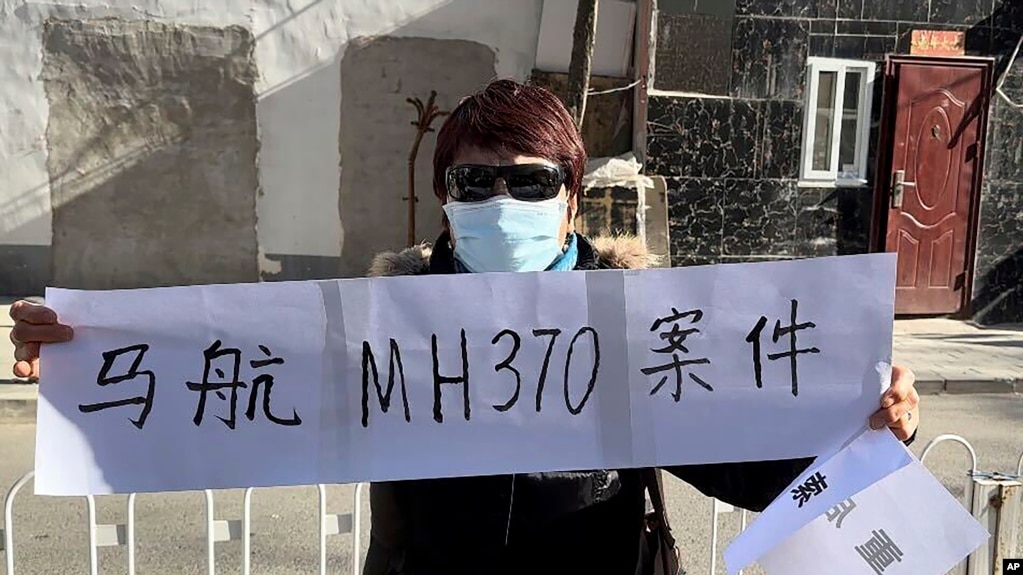 一名马航MH370航班乘客家属手拿标语。（美联社2023年11月27日）