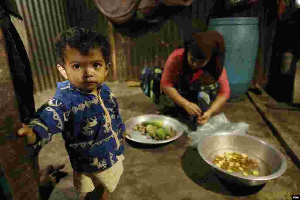 15-month-old Suhana stands by as her mother Sura Khatum prepares a meal in the family’s shelter at Kutupalong refugee camp Feb. 15, 2020. (Hai Do/VOA)