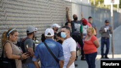 Inmigrantes en el programa "Permanezca en México" hacen fila en el Instituto de Inmigración Nacional de México para renovar su permiso de estadía mientras esperan cita en inmigración estadounidense.