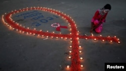 FILE - A girl lights earthen lamps during an HIV/AIDS awareness campaign on the occasion of World AIDS Day in Kolkata, India, December 1, 2021.