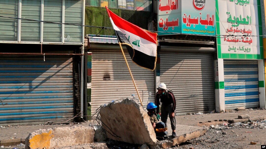 Anti-government protesters take cover during clashes with security forces on Rasheed Street, Baghdad, Iraq, Tuesday, Nov. 26, 2019.