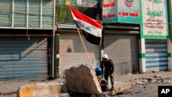 Anti-government protesters take cover during clashes with security forces on Rasheed Street, Baghdad, Iraq, Tuesday, Nov. 26, 2019.