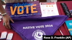 FILE - Voter information is on display at a Phoenix Indian Center booth during an Indigenous Peoples' Day event in Phoenix, Oct. 14, 2024. 